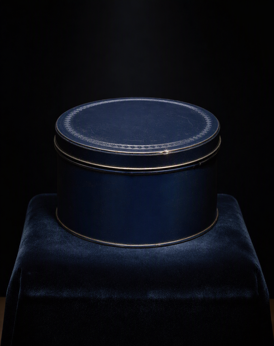 Lata redonda de esmalte azul oscuro con filo dorado, sobre terciopelo azul y fondo negro